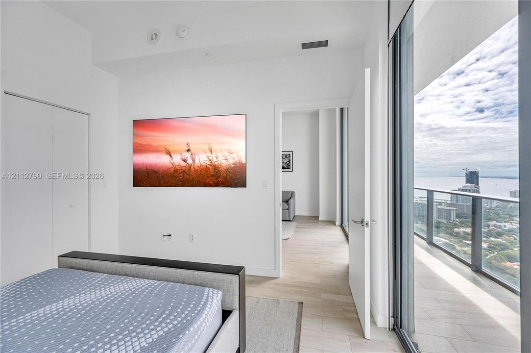 Floor-to-ceiling glass sliding doors, private balcony, wood-finish flooring, and high ceilings