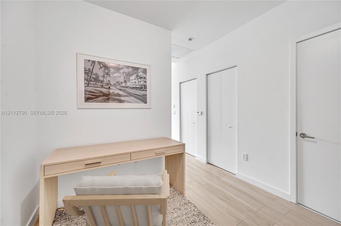 Wood-finish flooring, crisp white wall finishes, and multiple interior doors with modern hardware