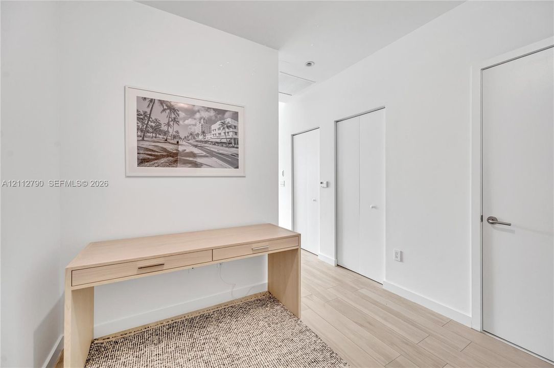 Neutral color palette featuring wood-finish flooring, smooth-panel doors, and built-in desk cabinetry