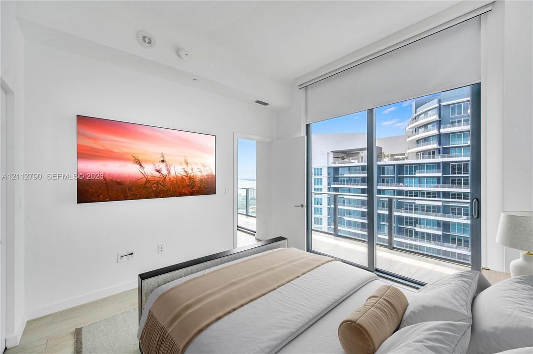 Floor-to-ceiling glass sliding doors, private balcony, wood-finish flooring, and recessed ceiling lighting