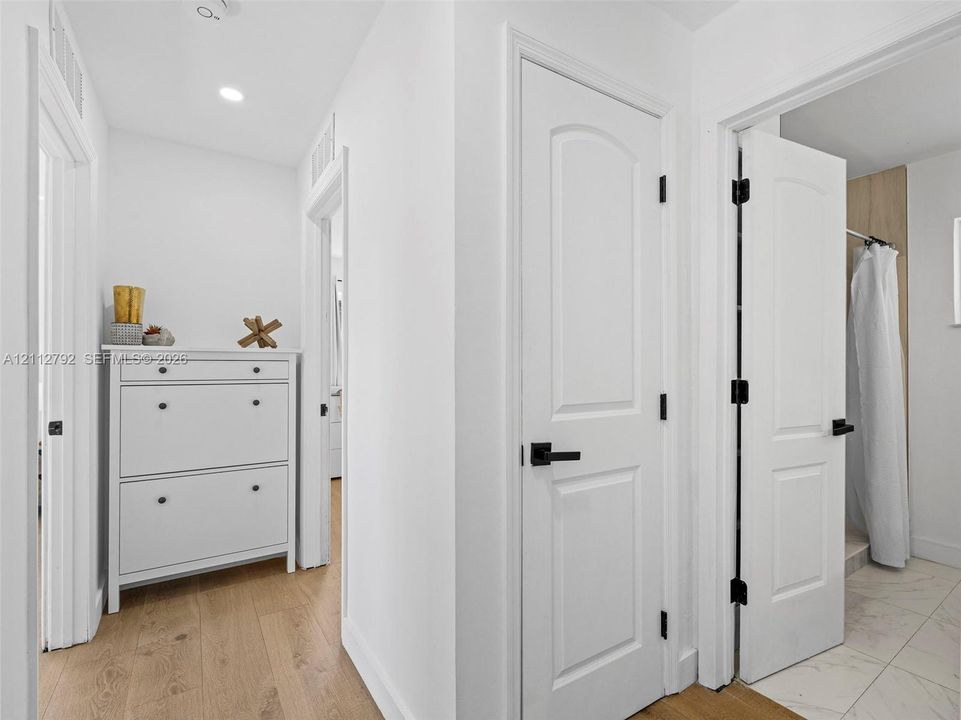 Hallway featuring wood-finish flooring, two-panel arched interior doors, and matte black hardware throughout