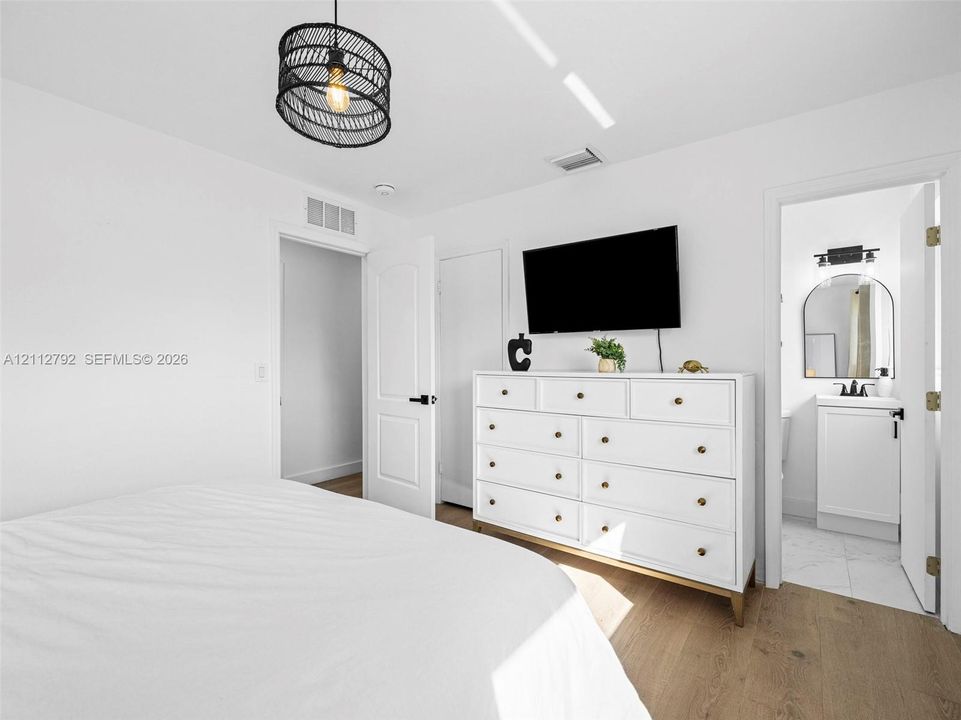 Wood-finish flooring, textured drum pendant lighting, and multi-panel interior doors with matte black hardware
