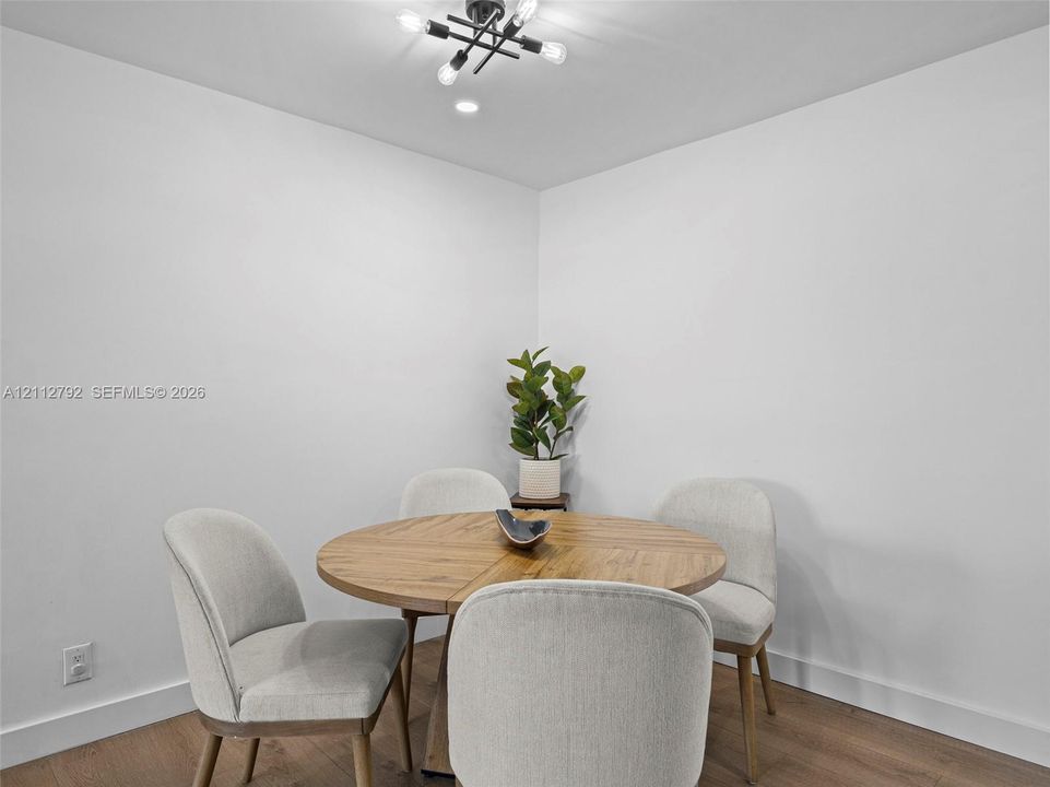 Wood-finish flooring, neutral walls, and a modern multi-bulb overhead light fixture
