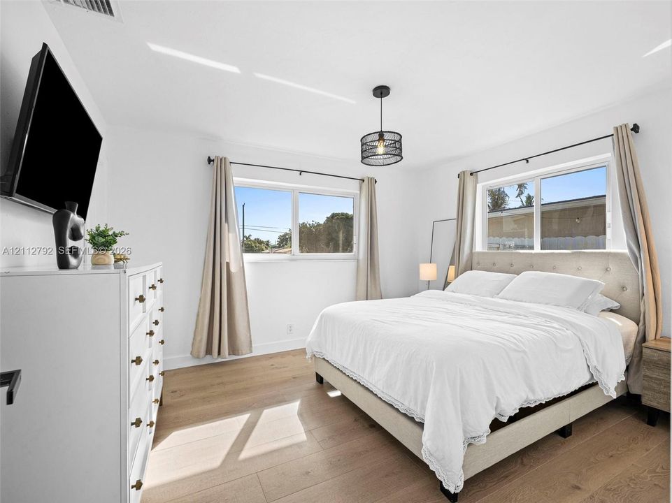 Room featuring wood-finish flooring, dual windows, and a cylindrical pendant light fixture