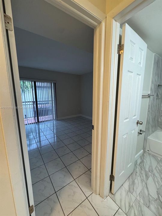 Interior featuring large-format stone-patterned tile flooring, six-panel interior doors, and sliding glass balcony doors