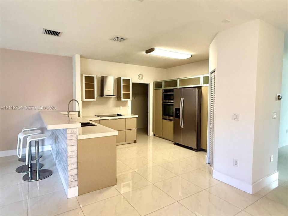 Kitchen featuring a peninsula with quartz countertops, stainless steel appliances, flat-panel cabinetry, and polished tile flooring