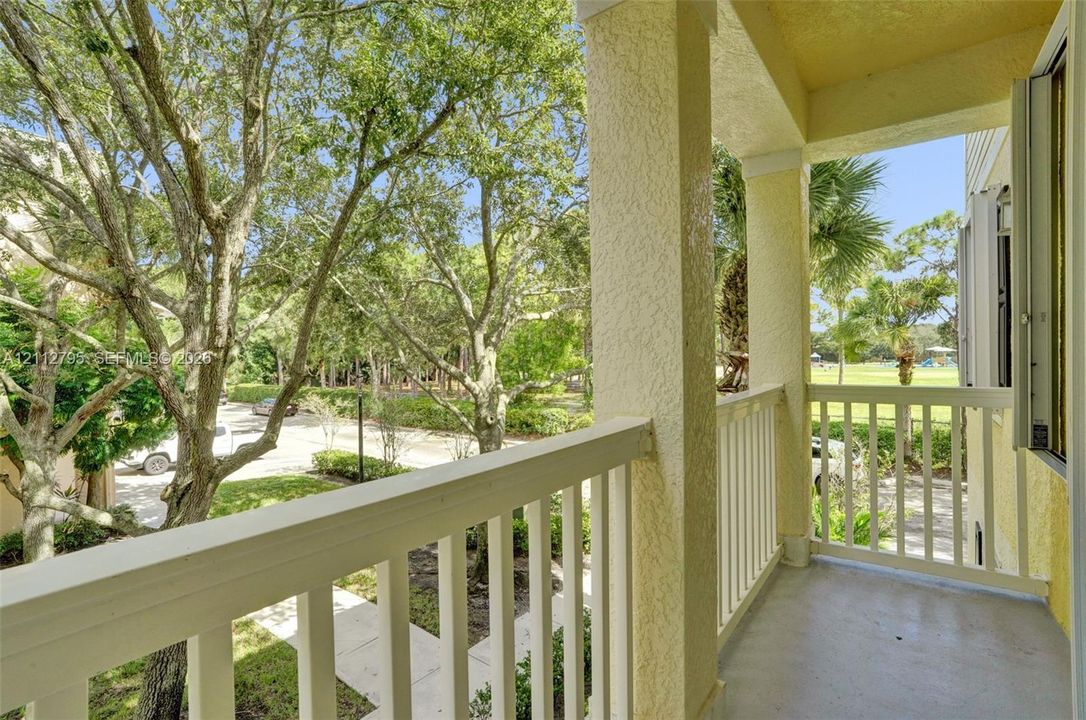 Covered balcony featuring white vertical railings, stucco columns, and concrete flooring
