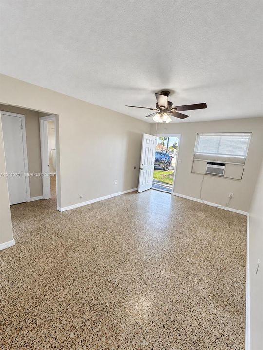 Polished terrazzo flooring, ceiling fan with integrated lighting, wall-mounted air conditioning unit, and interior passage doors