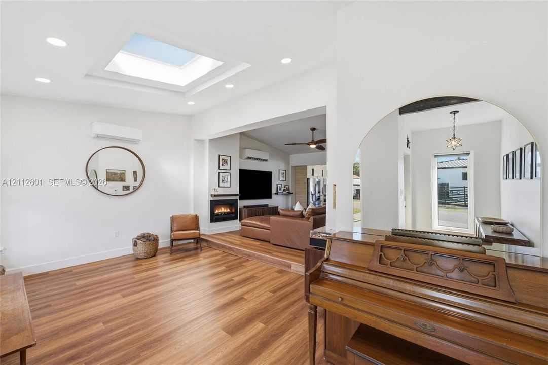 Open-concept living space featuring wood-finish flooring, a recessed ceiling skylight, recessed lighting, and an inset fireplace
