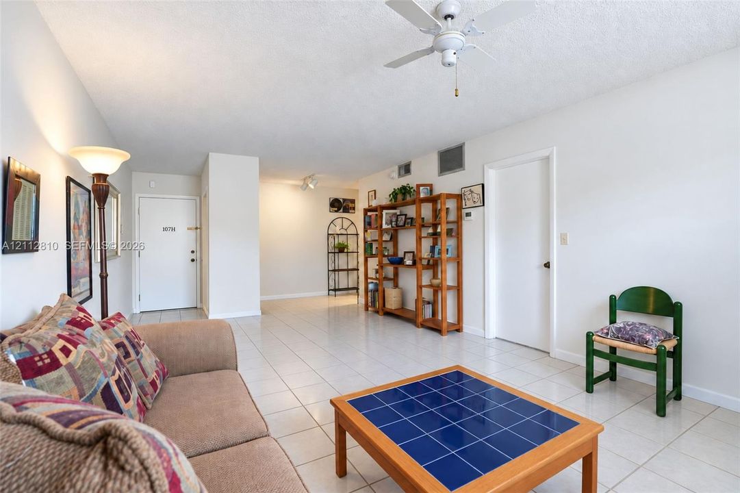 Interior space featuring neutral wall tones, large-format tile flooring, a white ceiling fan, and track lighting