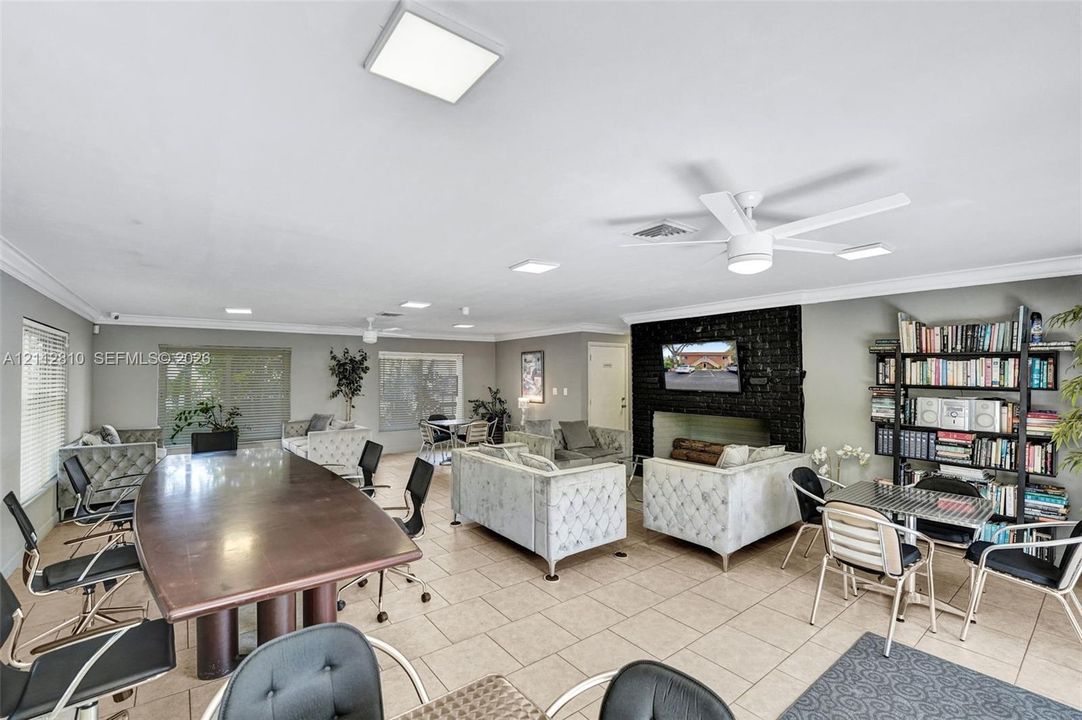 Open-concept area featuring oversized ceramic tile flooring, a dark masonry fireplace, built-in shelving, recessed lighting, and white ceiling-mounted fans