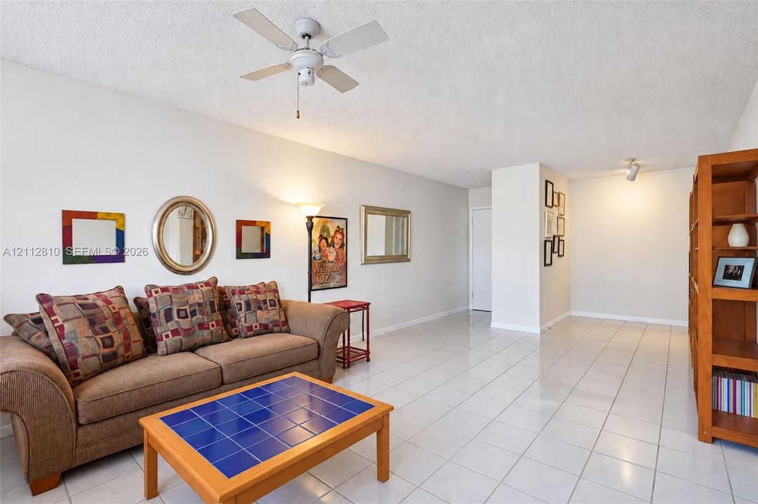 Living area featuring light-toned ceramic tile flooring, a textured ceiling finish, and a center-mounted ceiling fan with light fixture