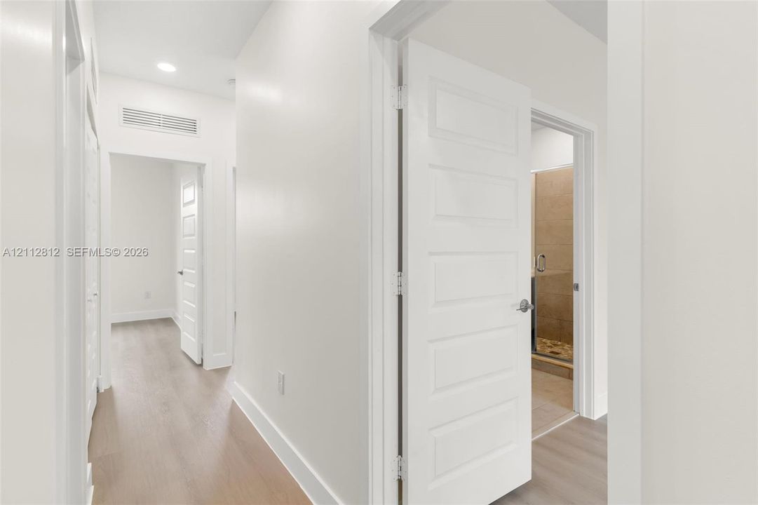Hallway featuring wood-finish flooring, five-panel interior doors, and recessed lighting
