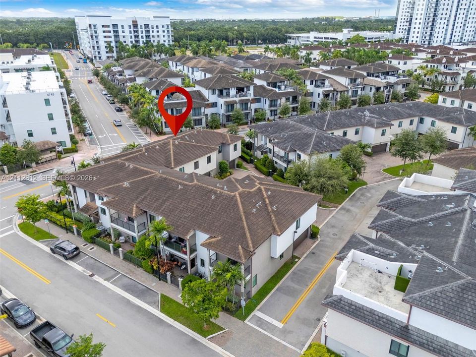 Multi-level townhome featuring a hip roof, stucco exterior, private balconies, and integrated garage access