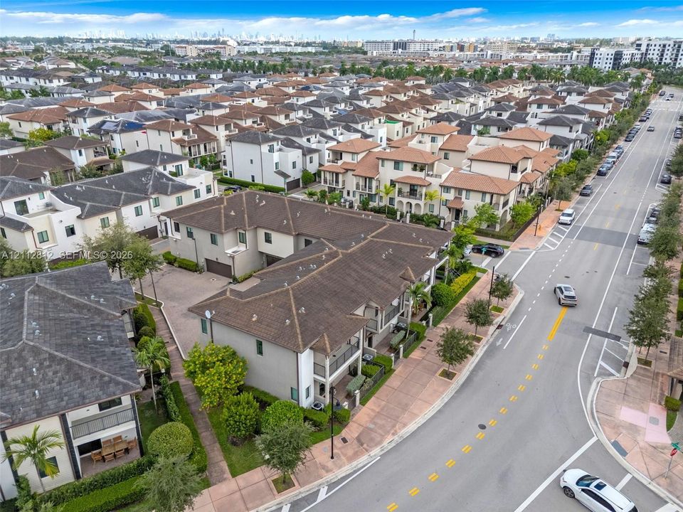 Multi-unit residential structure featuring a hip roof, stucco exterior, paved driveway, and established landscaping