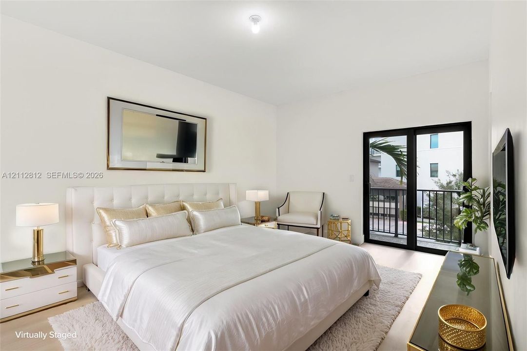 Neutral-toned interior featuring wood-finish flooring, crisp white walls, and black-framed glass sliding doors opening to an exterior balcony