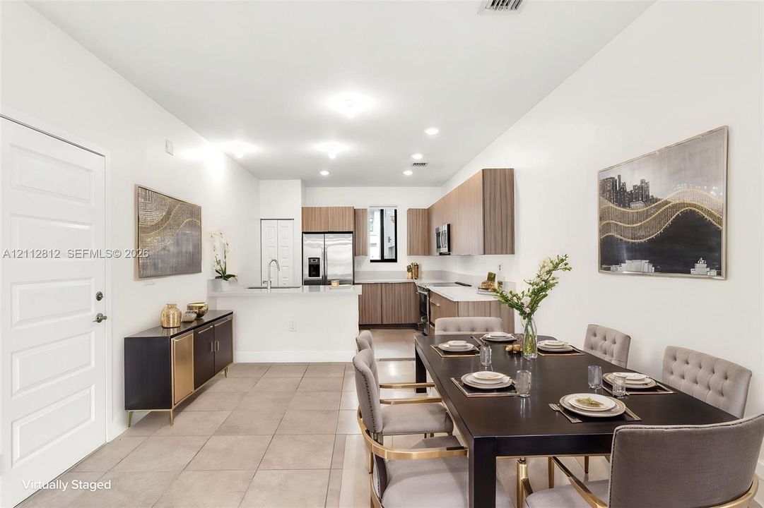 Kitchen featuring flat-panel wood-finish cabinetry, light-toned stone-finish countertops, stainless steel appliances, and large-format tile flooring