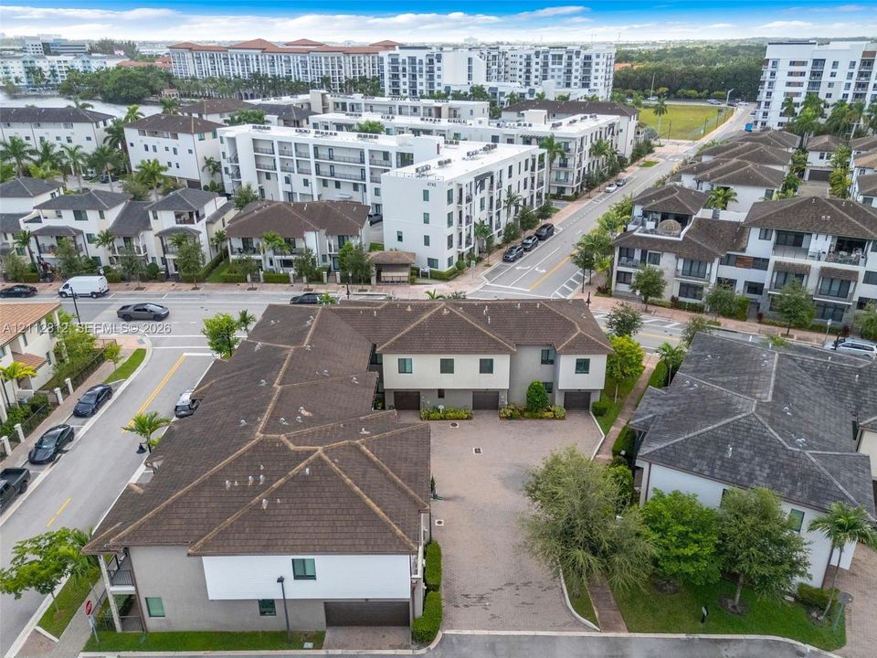 Multi-unit residential complex featuring a paved motor court, integrated garage entrances, and pitched shingle roofing
