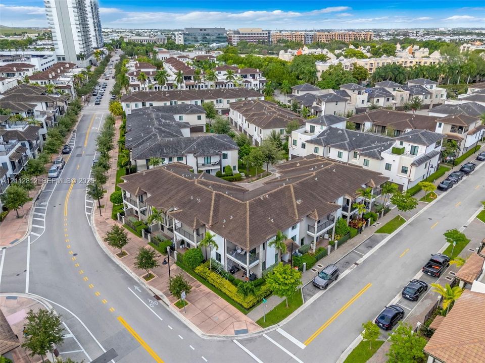 Aerial perspective of a multi-unit residential development featuring tile roofing, stucco siding, integrated private balconies, and landscaped grounds