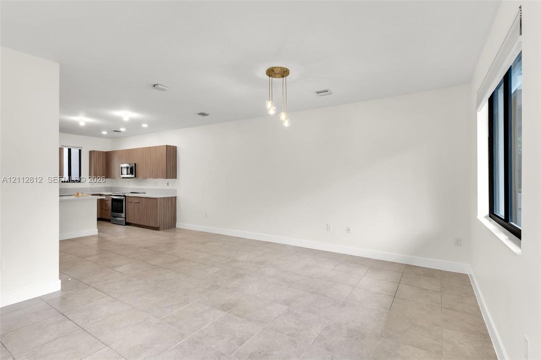 Open floor plan featuring tile flooring, neutral wall tones, recessed lighting, and a kitchen equipped with wood-finish cabinetry and stainless steel appliances