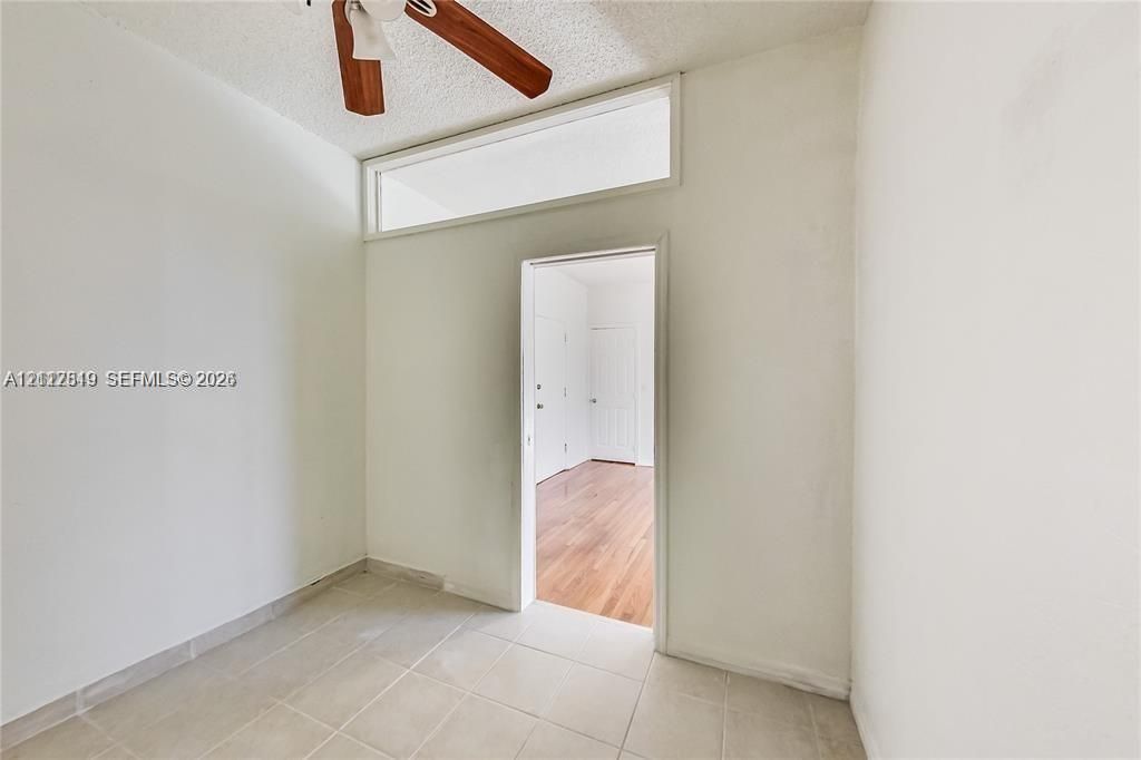 Interior space featuring large rectangular transom window, neutral ceramic tile flooring, and ceiling fan with wood-finish blades