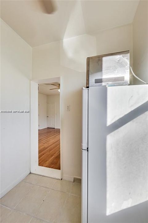 Kitchen area featuring a white refrigerator with a stainless steel microwave and light-toned tile flooring