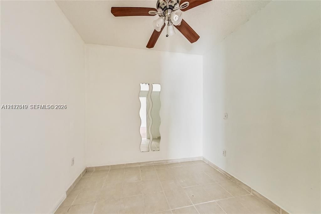 Room featuring neutral tile flooring, white walls, and a ceiling fan with integrated lighting
