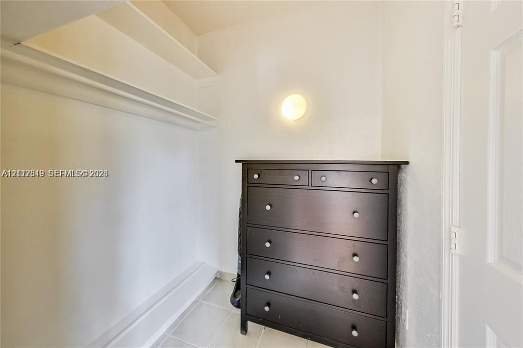 Storage area featuring built-in shelving, tile flooring, and a wall-mounted globe light fixture