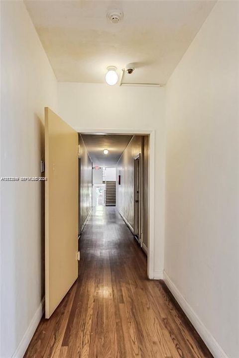 Hallway featuring wood-finish flooring, ceiling-mounted lighting, and solid core doors