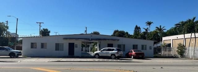 Single-story commercial building featuring a white stucco exterior, flat roofline, and paved frontage