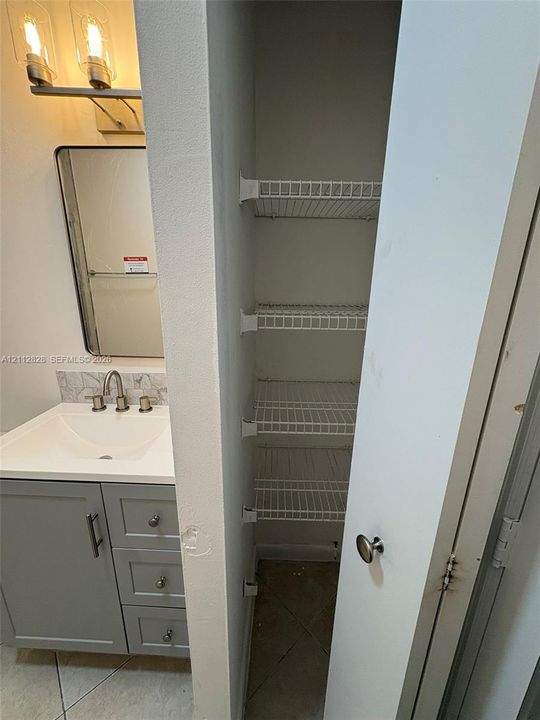 Vanity featuring grey shaker-style cabinetry, a solid-surface countertop with an integrated basin, a polished nickel widespread faucet, and a rectangular mirror