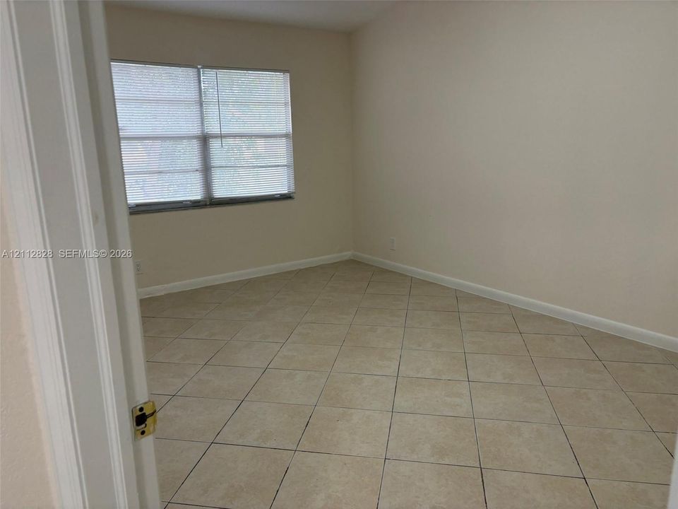 Neutral-toned room featuring diagonal tile flooring and large windows with horizontal blinds
