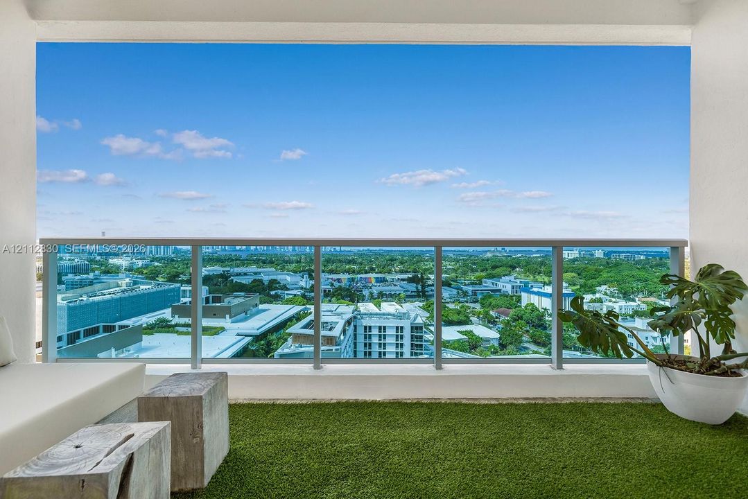 Private balcony featuring synthetic turf surfacing and a glass-paneled railing with metal framing