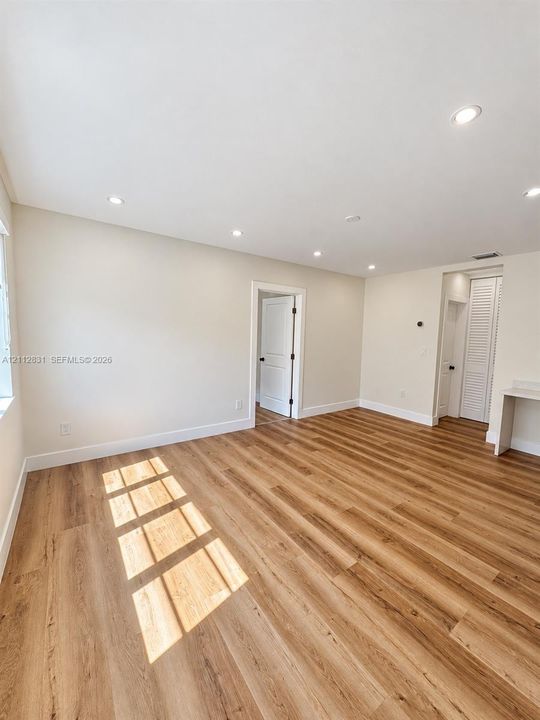 Wood-finish flooring, recessed lighting, neutral wall paint, and multi-panel interior doors