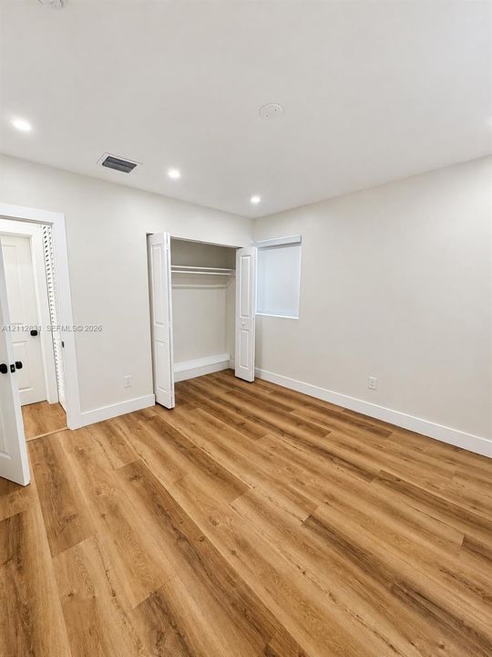 Interior room featuring wood-finish flooring, recessed lighting, neutral wall paint, and a built-in closet with double-hinged doors