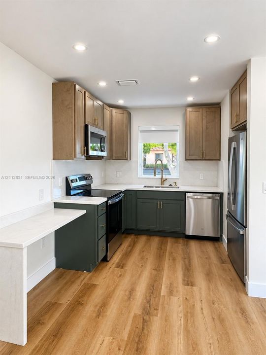 Kitchen featuring wood-finish flooring, two-tone cabinetry, stone-surface countertops, recessed lighting, and stainless steel appliances