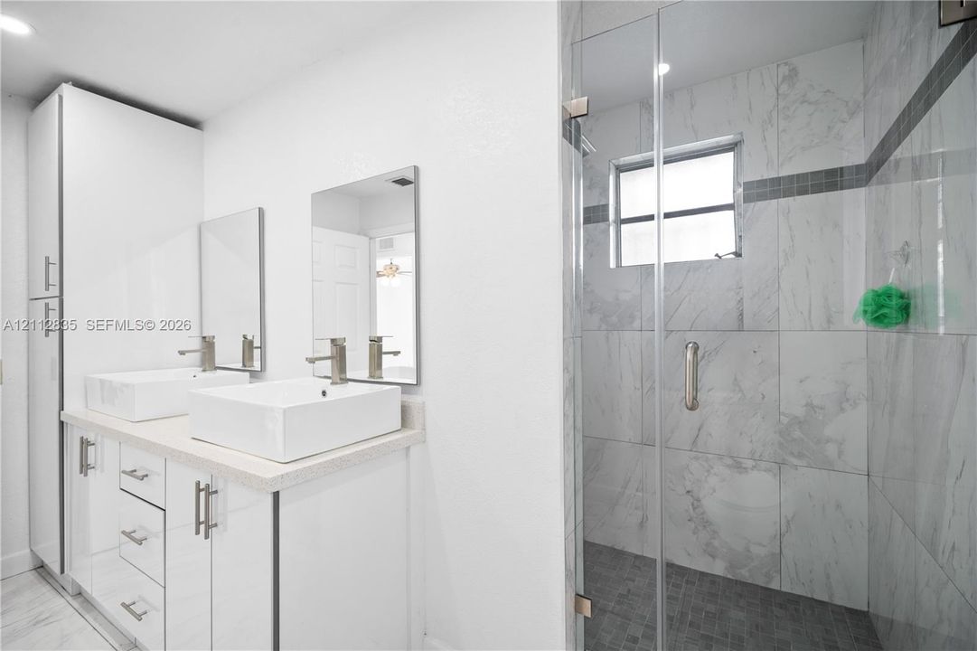 Enjoy the convenience of a glass-enclosed shower and separate double sinks.