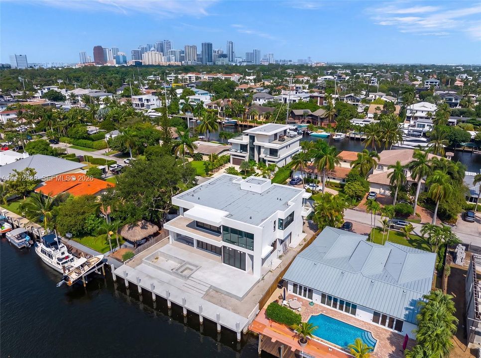 Waterfront property featuring a multi-level contemporary structure, expansive concrete terrace, built-in fire feature, private dockage, and deep-water canal access