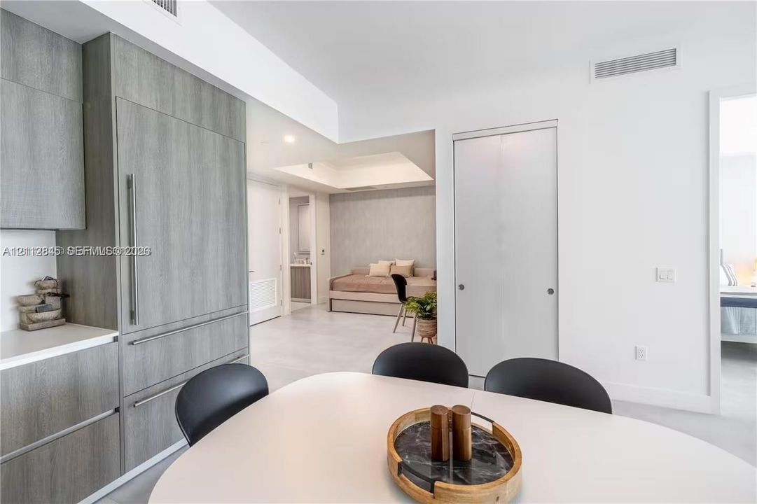 Modern kitchen cabinetry with wood-finish paneling, integrated refrigerator, white stone countertops, and tile flooring