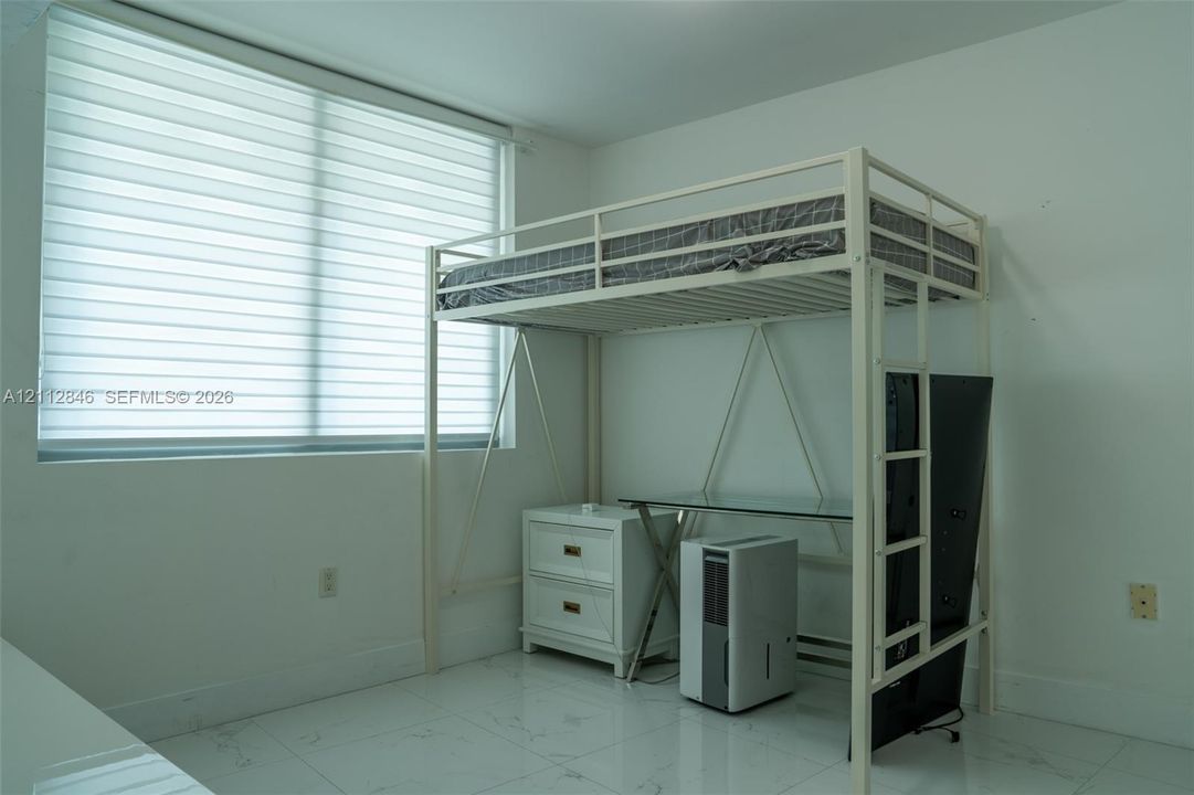 Large window featuring horizontal light-filtering shades and polished tile flooring