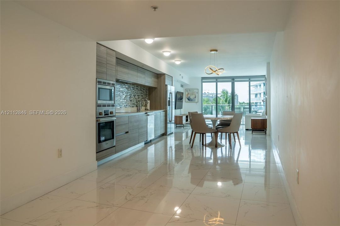 Kitchen featuring horizontal-grain cabinetry, stainless steel wall oven and microwave, mosaic tile backsplash, and floor-to-ceiling glass panel windows