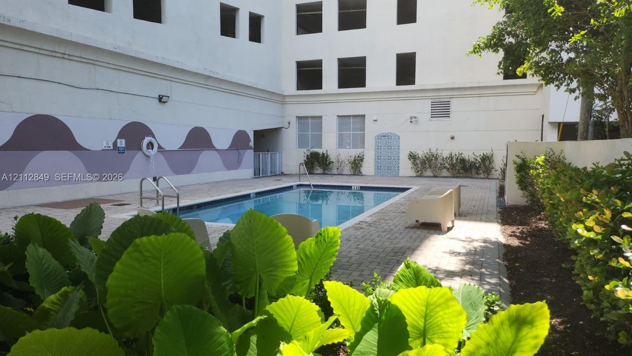 Swimming pool with paver decking, decorative wall mural, and manicured perimeter landscaping