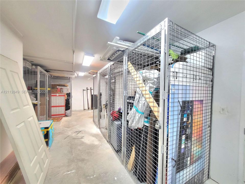 Dedicated storage area featuring reinforced metal grid partitions, locking cage doors, and integrated linear lighting