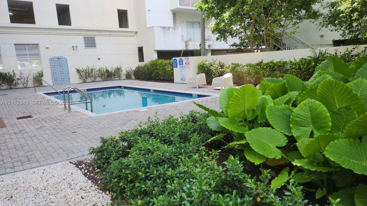 Swimming pool with paved surround, decorative tiled wall accent, and landscaped perimeter featuring mature foliage