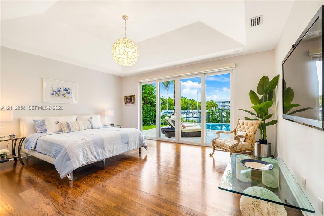 Vaulted ceiling with decorative pendant lighting, wood-finish flooring, and expansive sliding glass doors providing outdoor access