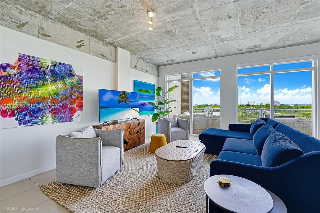 Exposed concrete ceiling, floor-to-ceiling windows, and large-format tile flooring