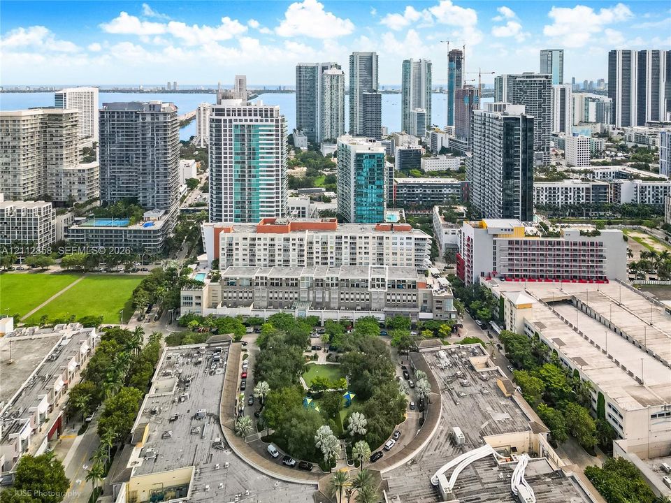 Aerial perspective of the urban landscape featuring high-rise buildings, a central green space with mature trees, and proximity to the waterfront