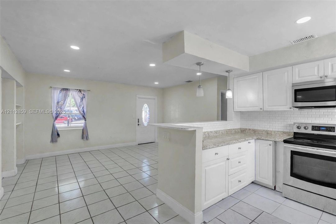 Kitchen featuring white cabinetry, stone-finish countertops, subway tile backsplash, stainless steel appliances, and recessed lighting throughout the area