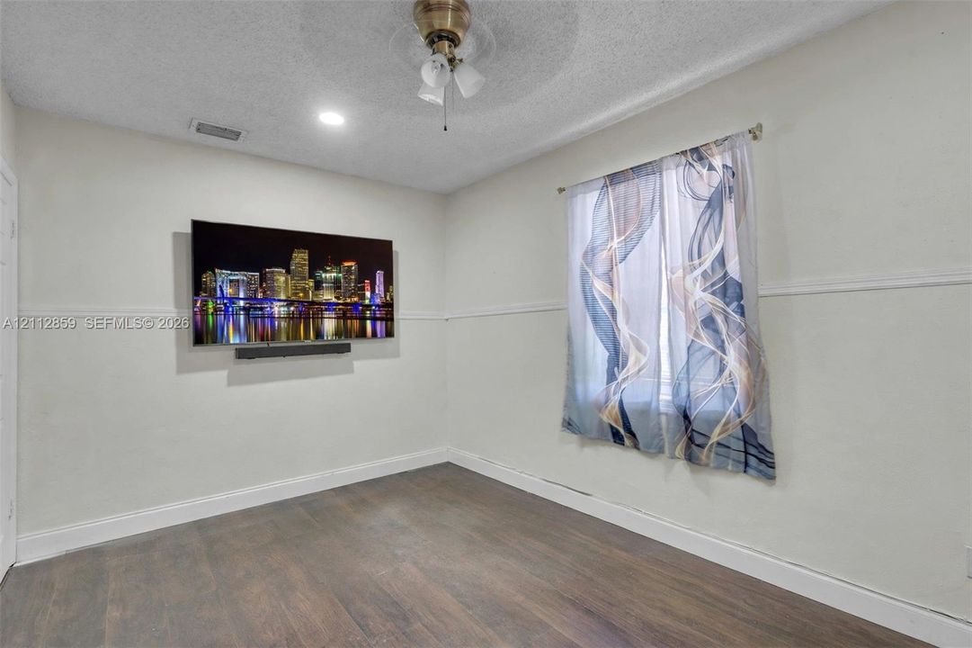 Room featuring wood-finish flooring, a ceiling fan with integrated lighting, a recessed ceiling light, and horizontal chair rail molding