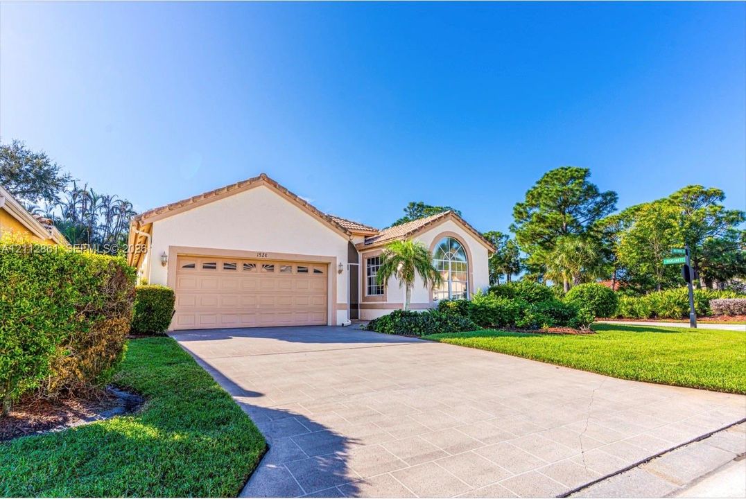Single-story residence featuring a multi-pane arched window, a paved driveway, and an attached multi-car garage